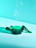 A hunter green bathing lady dish on a turquoise background.