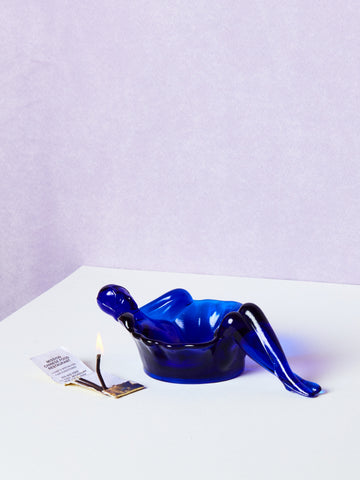 Blue plastic bathing lady dish on a white surface with a light purple background