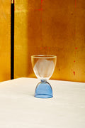 A clear top blue bottom cocktail glass.