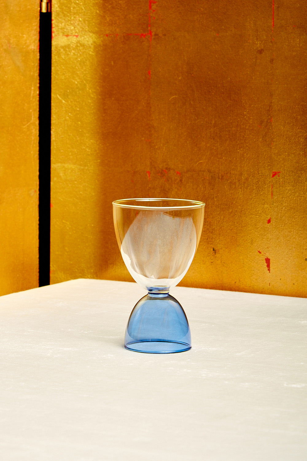 A clear top blue bottom cocktail glass.