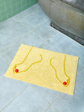 Yellow bath mat with footprints on a tiled bathroom floor