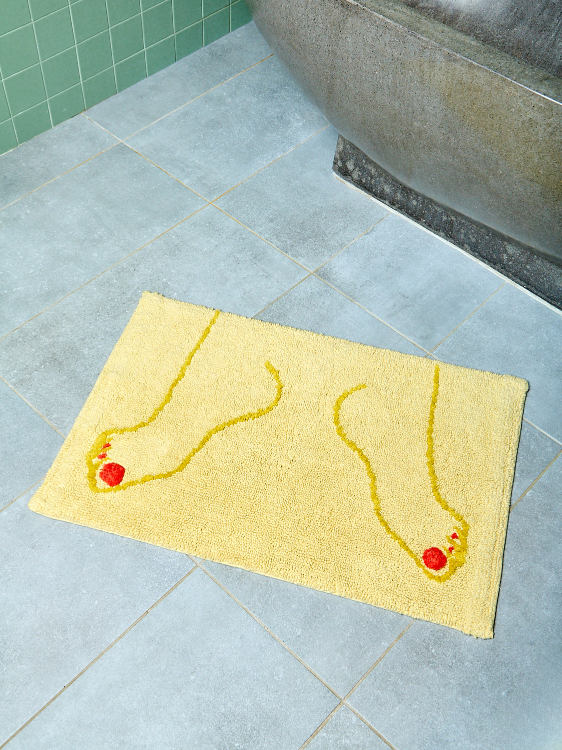 Yellow bath mat with footprints on a tiled bathroom floor
