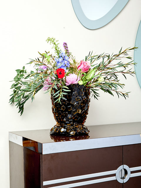 Decorative resin vase with mosaic tile design, holding flowers.