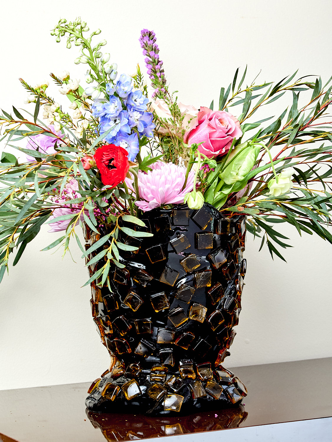 Decorative resin vase with mosaic tile design, holding flowers