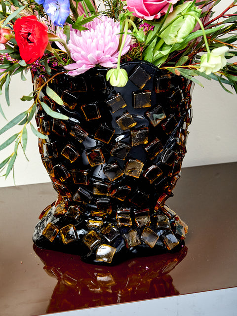 Decorative resin vase with mosaic tile design, holding flowers.
