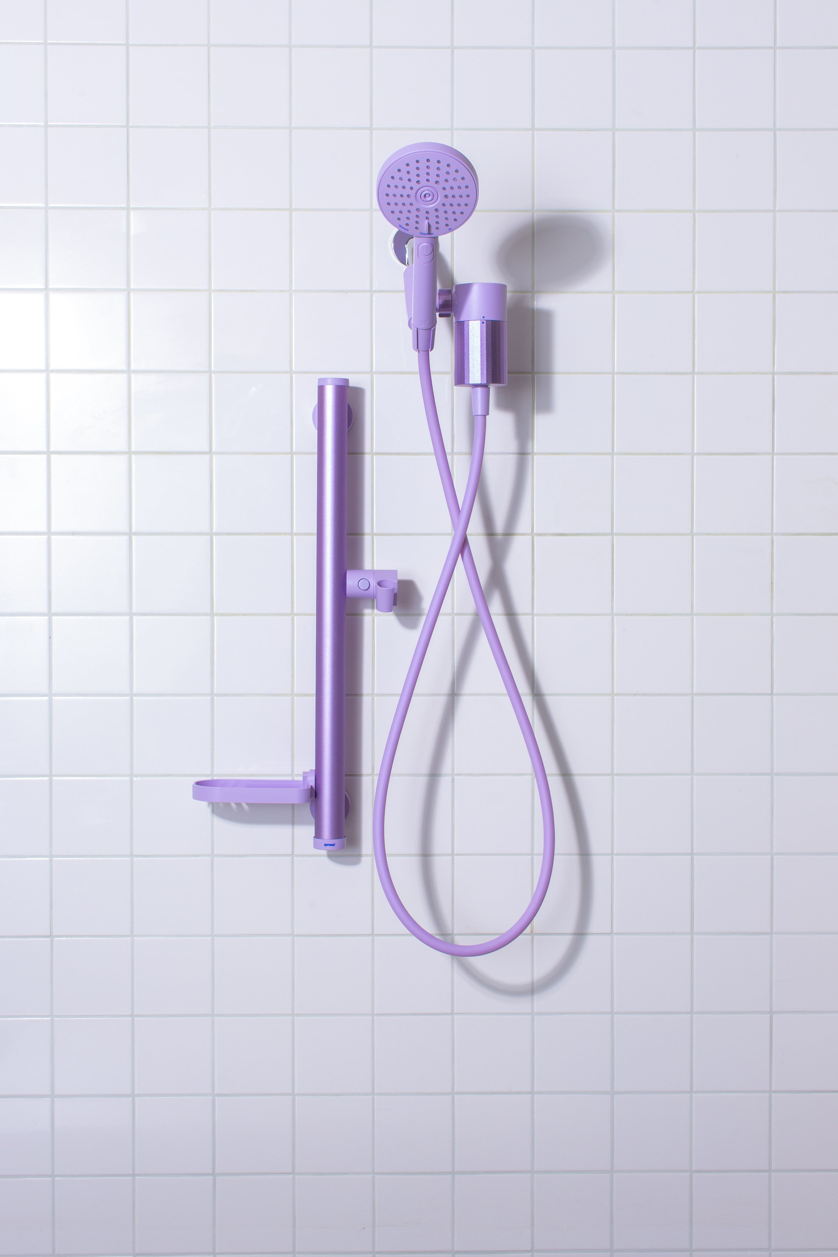 Lavender shower head and hose on a tiled wall background