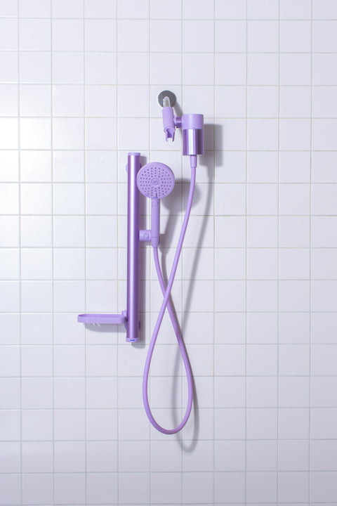 Lavender shower set with handheld showerhead and control handle on a tiled wall background