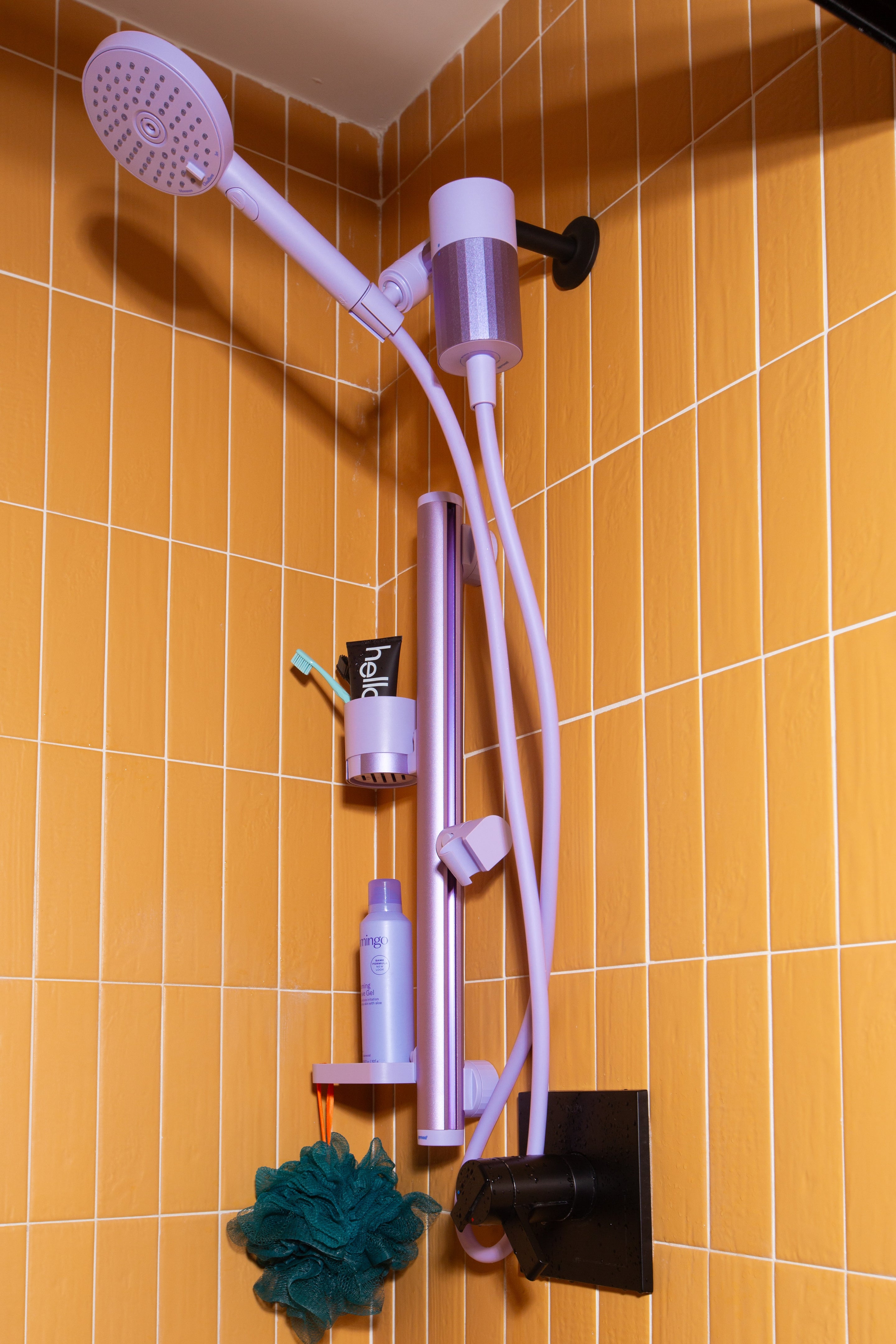 Lavender shower head and accessories on a tiled bathroom wall