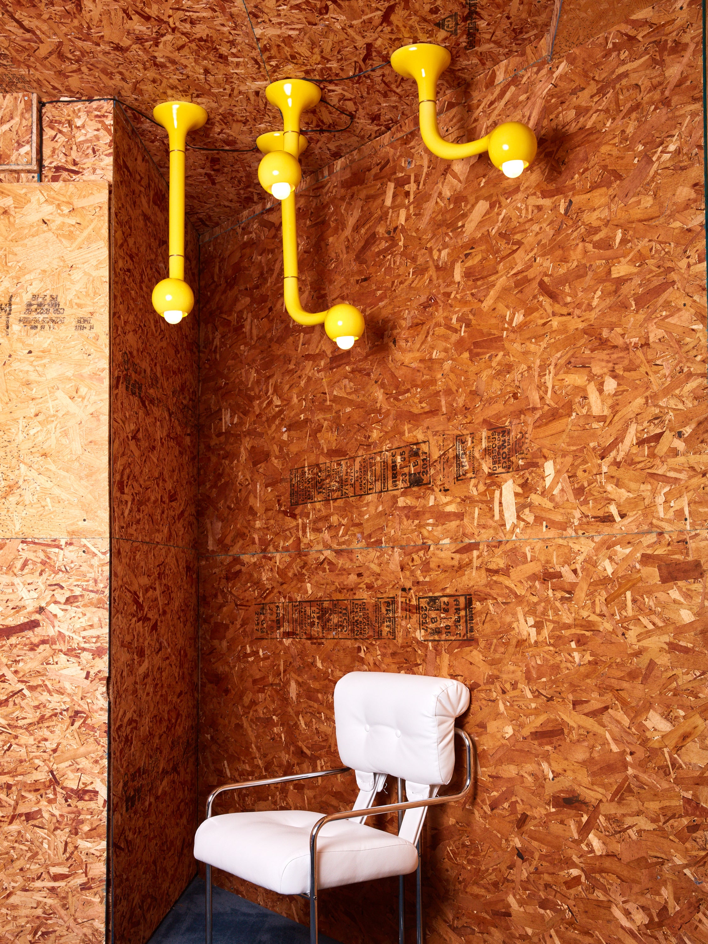 Four ceramic ceiling lamps by Entler Studio in a plywood room above a pink chair.
