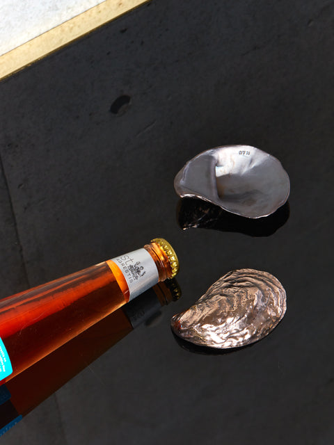 A bottle lays beside two oyster bottle openers.